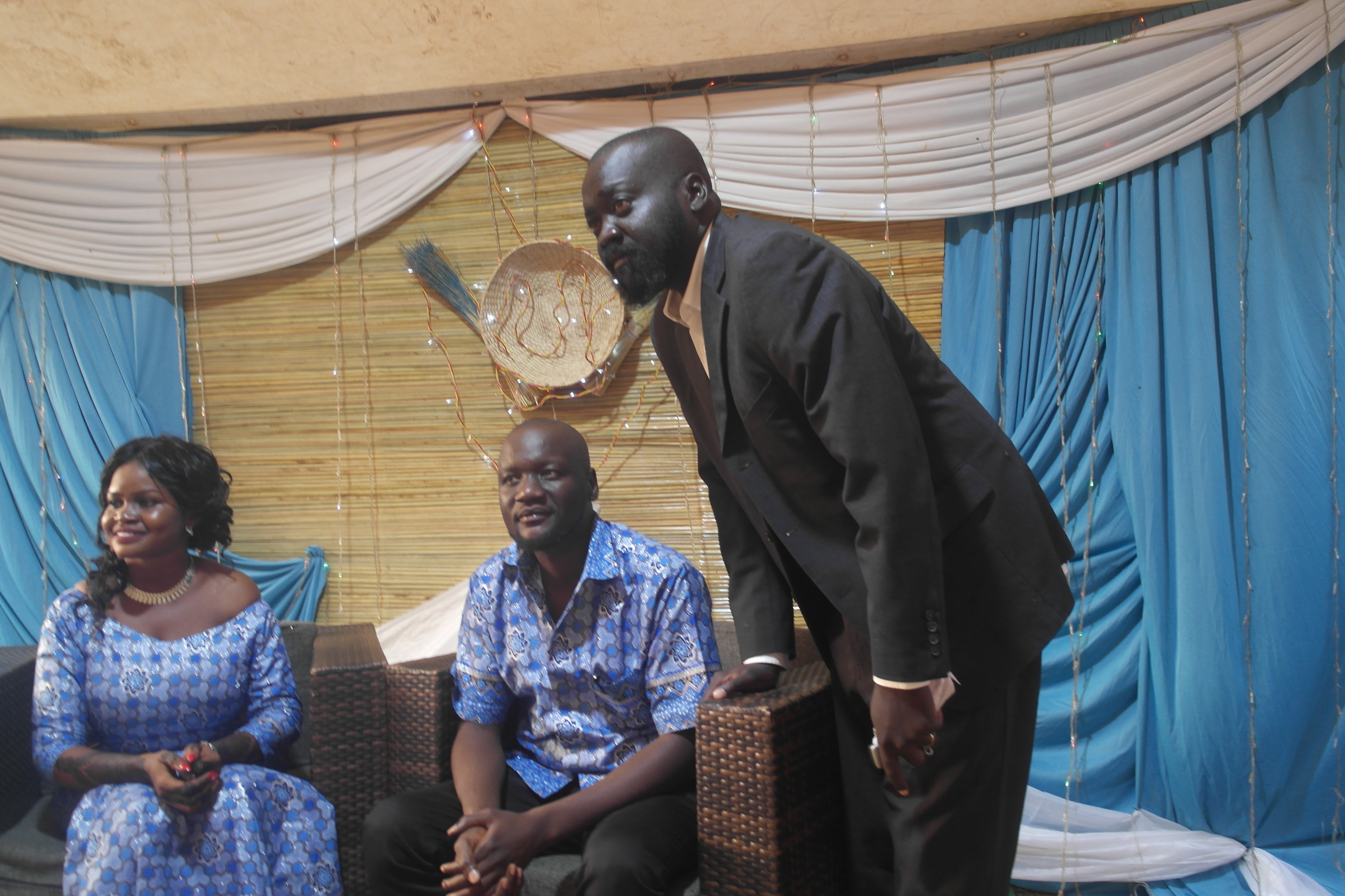 Labana standing beside a seated couple at a celebration